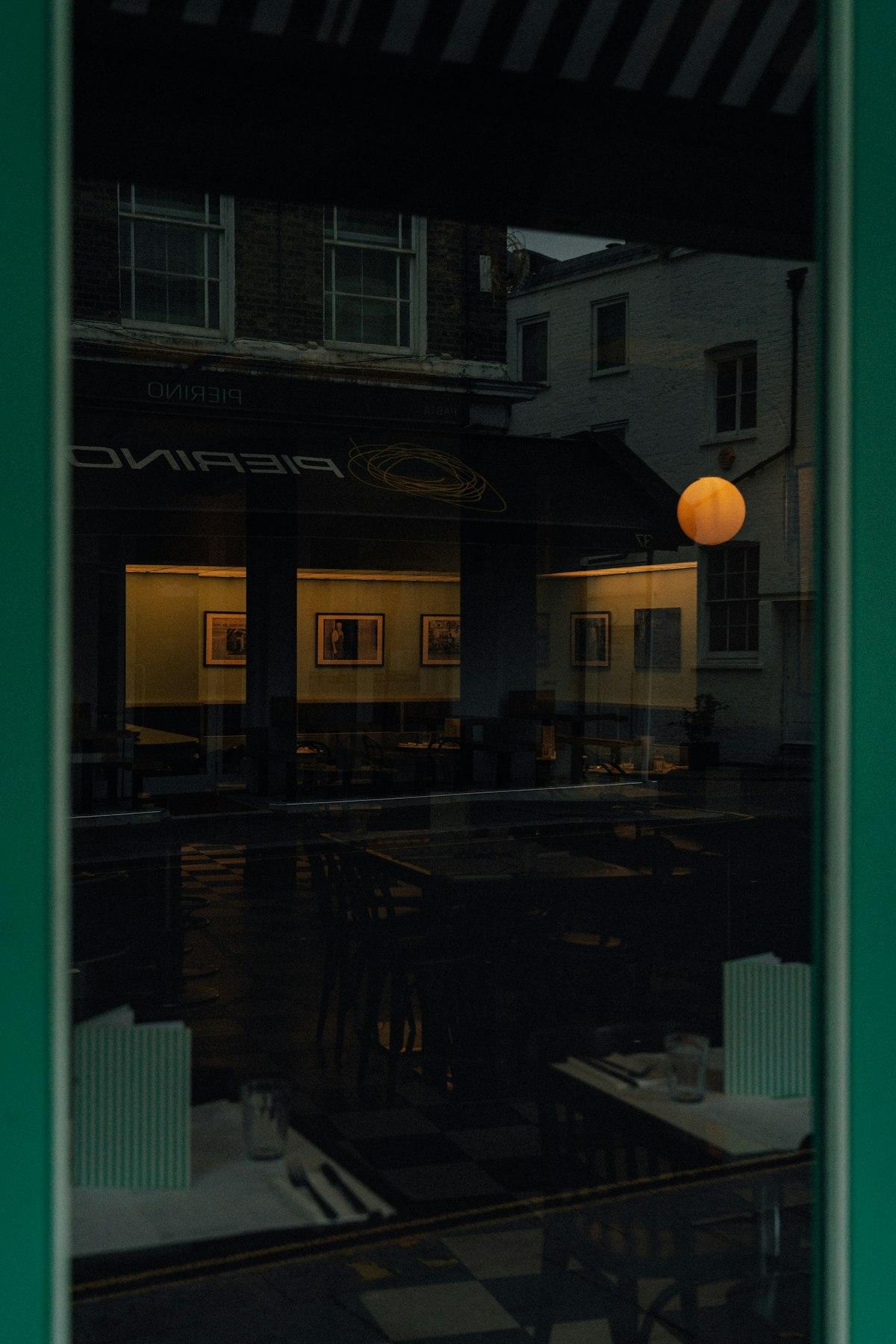 A softly lit dining room seen through reflective window glass.